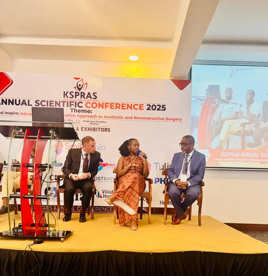 Dr Christine Nyabuto speaks into a microphone while seated between two fellow panellists on the KSPRAS Annual Scientific Conference 2025 stage.